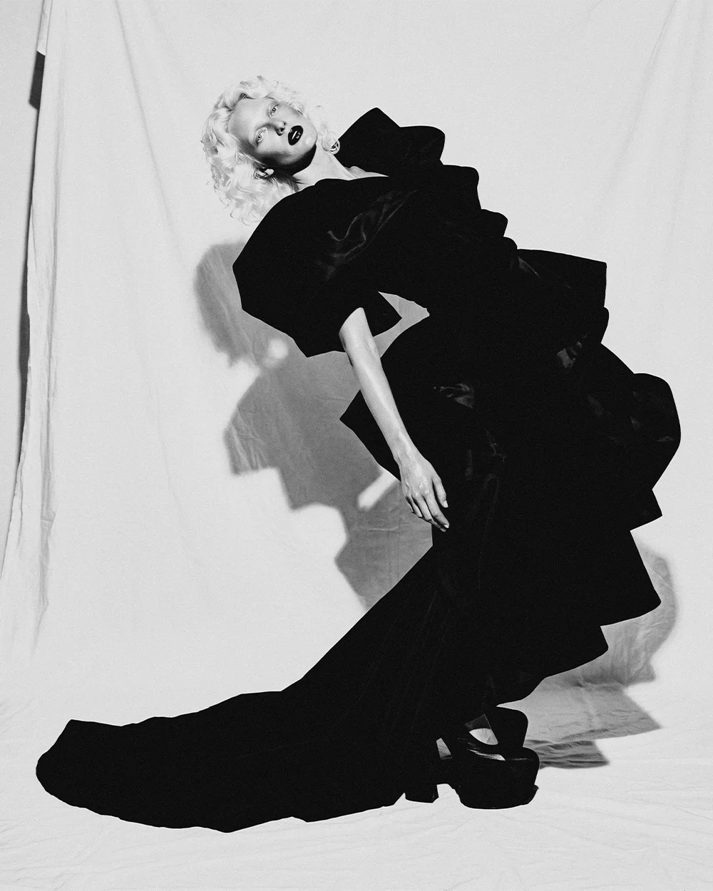Black and white full-length editorial of Elena arched backward in a black velvet gown with train against a white backdrop – Sbranzo Alessandro Valori Studio Vago Elena