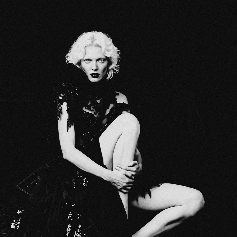 Black and white editorial portrait of Elena seated with raised knee in a black sequined lace gown – Sbranzo Alessandro Valori Studio Vago Elena