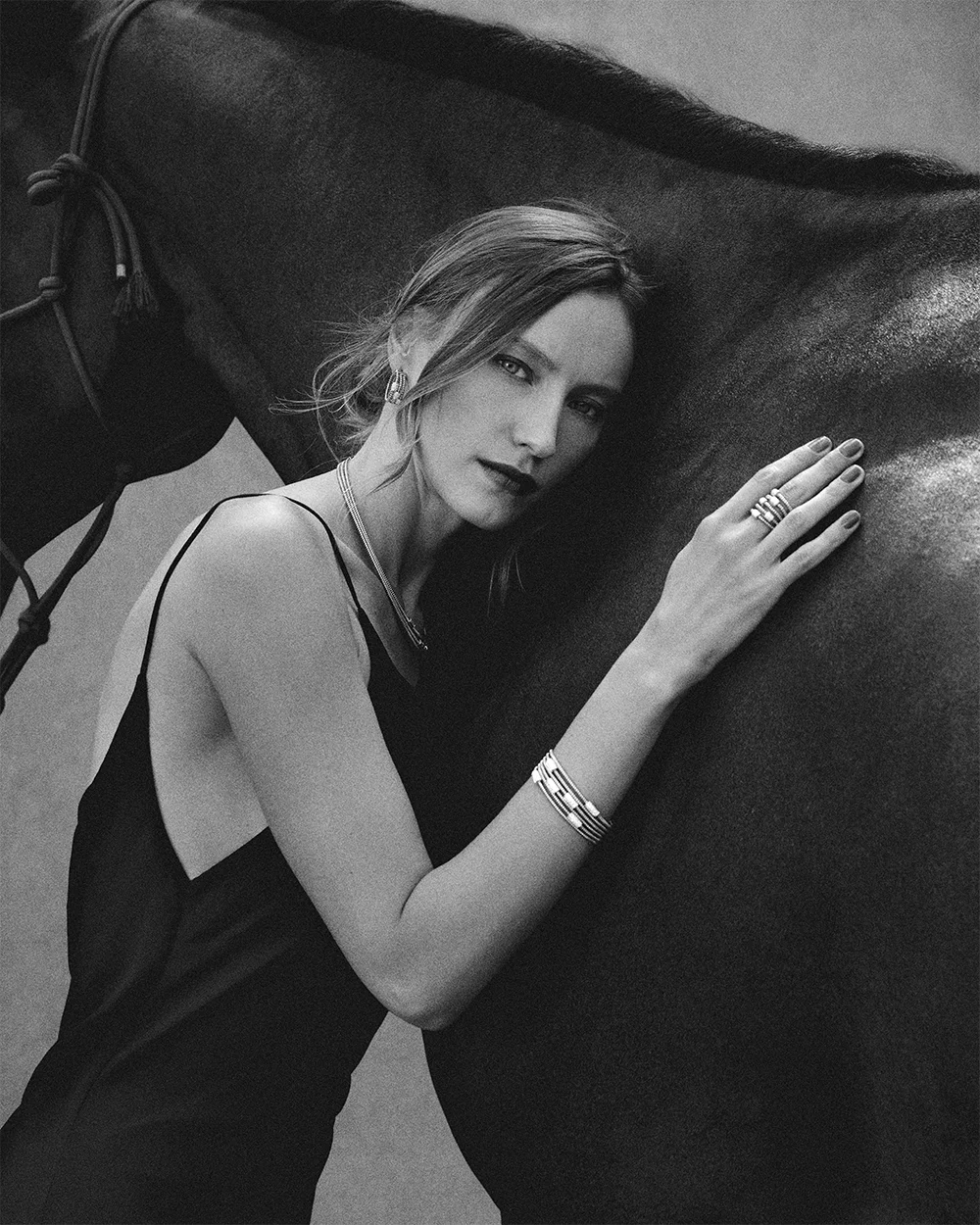 Black and white fashion jewelry editorial 999 – model resting hand on a horse wearing a necklace, bracelet and rings – Sbranzo Alessandro Valori Studio Vago Valeria Miro