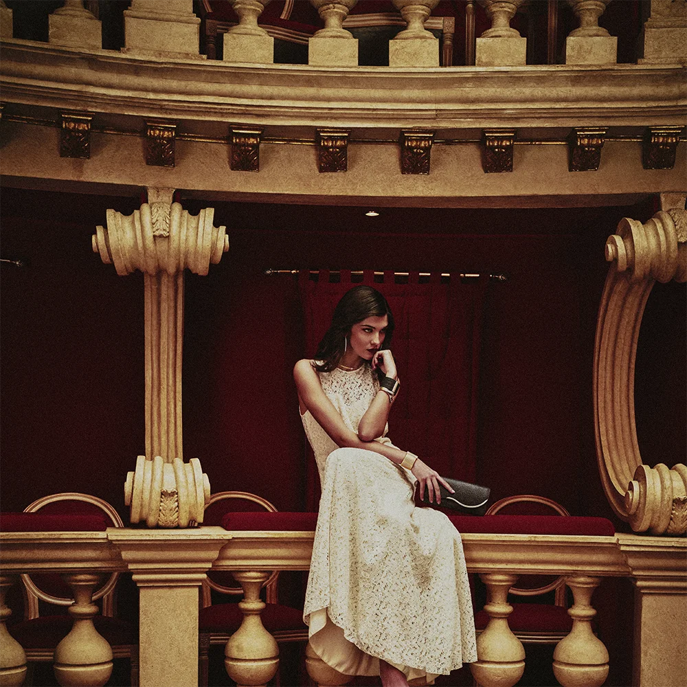 Fashion jewelry editorial 999 – full-length model in a white lace dress wearing a necklace, bracelet and earring in a gilded theatre interior – Sbranzo Alessandro Valori Studio Vago Tati Janusheva
