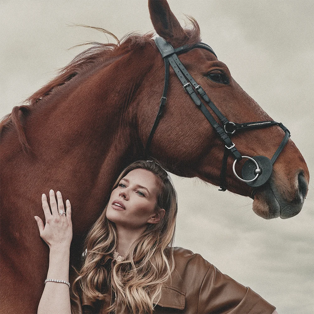 Fashion jewelry editorial – model resting against a chestnut horse wearing a diamond ring and tennis bracelet in a brown leather jacket – Sbranzo Alessandro Valori Studio Vago