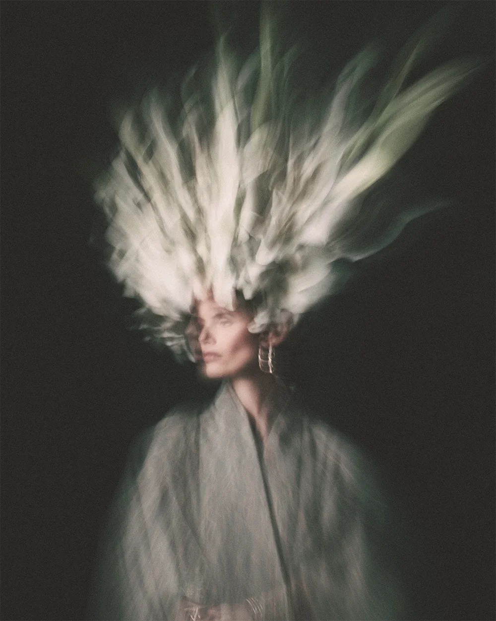 Editorial 999 – full-length double-exposure portrait of a model crowned with a white lily headpiece, wearing stacked gold bangles and rings over a floral patterned kimono, low-key chiaroscuro light and painterly dark background – Sbranzo Alessandro Valori Studio Vago