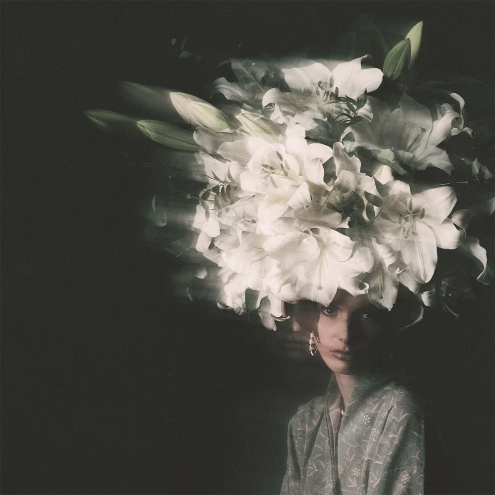 Editorial 999 – low-key portrait of a model crowned with white lilies, hoop earring and floral patterned kimono against a dark background – Sbranzo Alessandro Valori Studio Vago