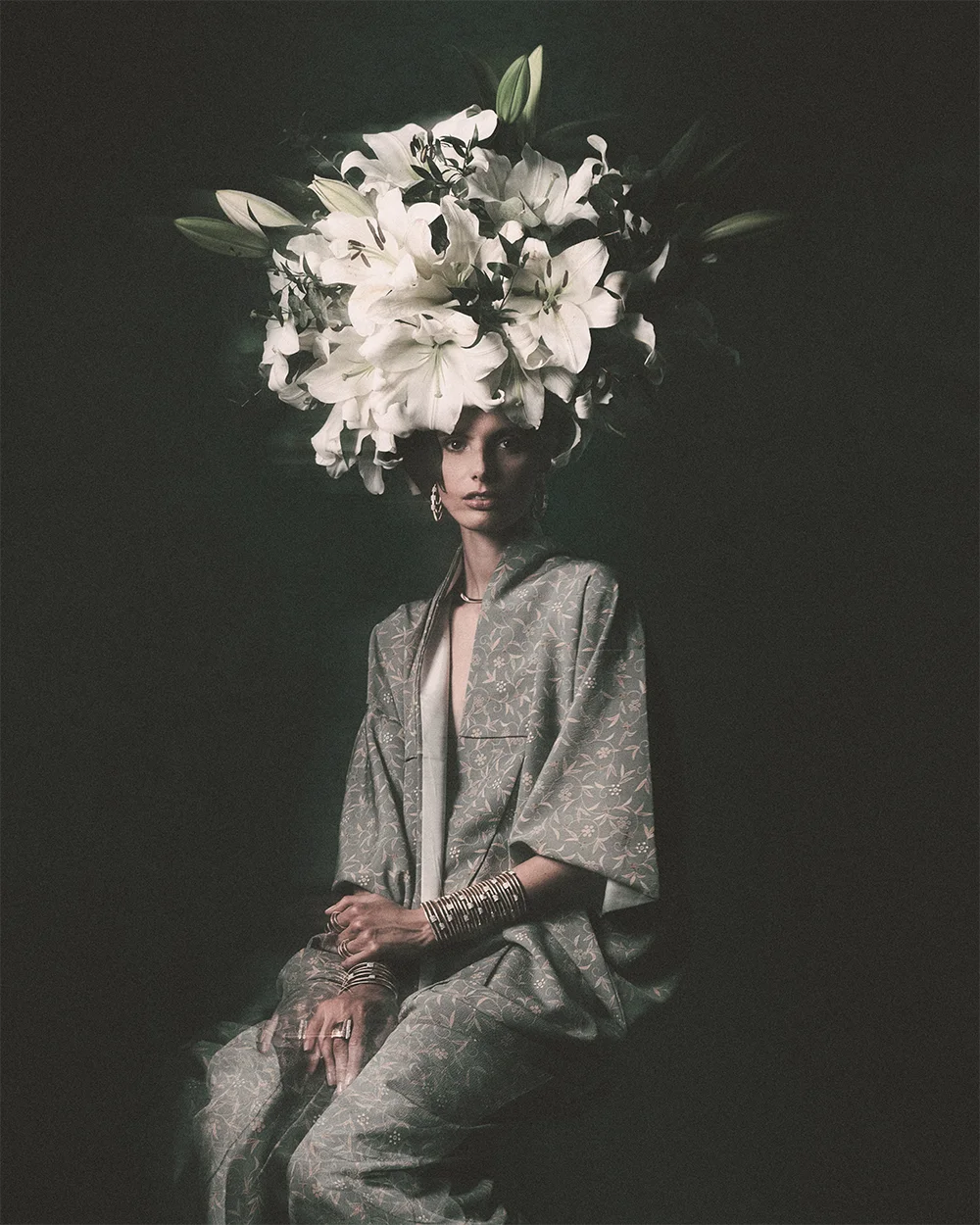 Editorial 999 – low-key seated portrait of a model crowned with white lilies wearing stacked gold bangles and rings with a floral patterned kimono, chiaroscuro light – Sbranzo Alessandro Valori Studio Vago